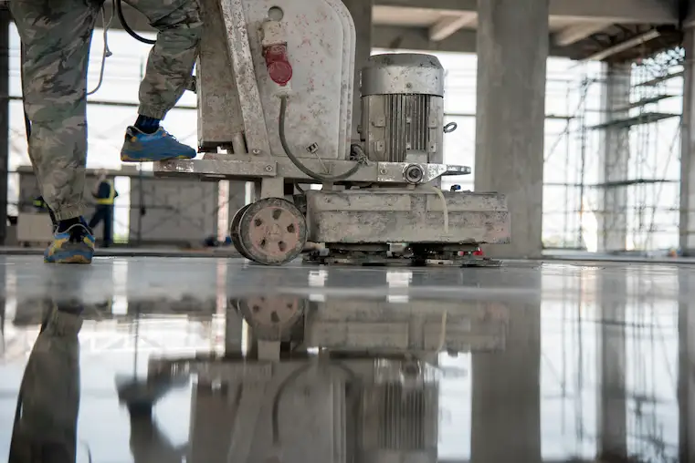 Persona limpiando el piso de concreto con una pulidora